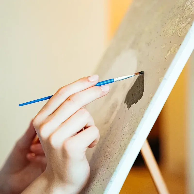 Painting a paint by numbers canvas with a brush
