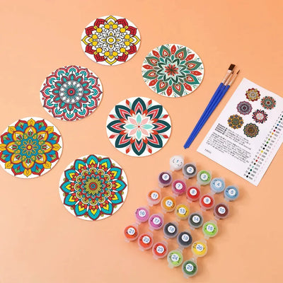 Pre-painted mandala coasters, paints, brushes, and a color card on the table