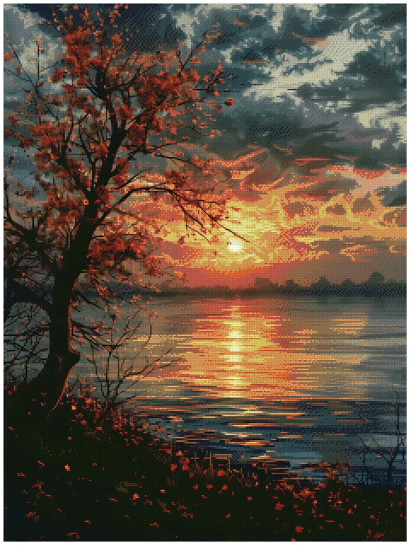 Diamond painting model image – a tree with red leaves reflects from calm water, an intense sunset in shades of orange, yellow, and dark red on the horizon, dark clouds above.