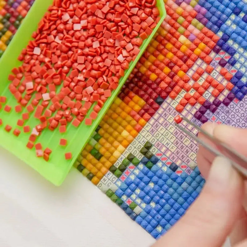 A person placing a diamond on the diamond work with tweezers