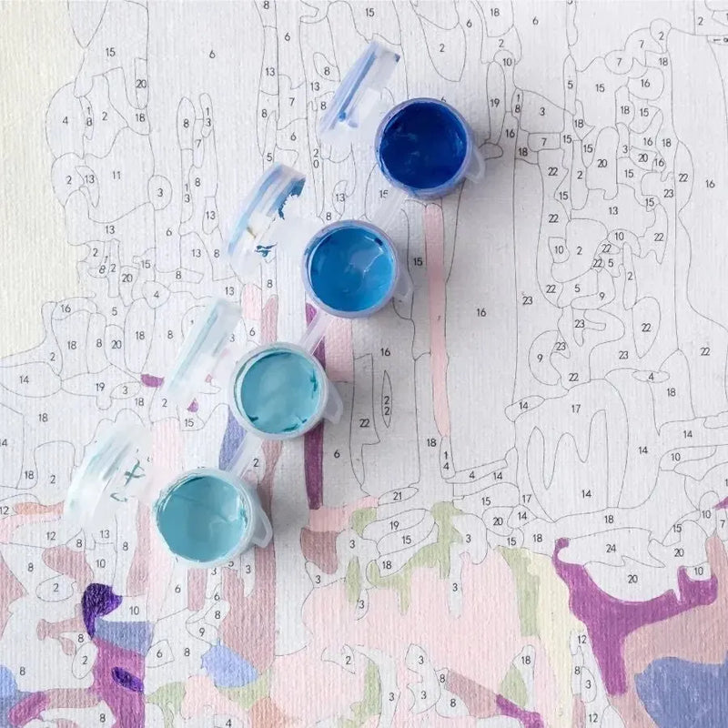 Paint by numbers partially painted with open paint jars on top