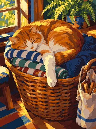 Orangevit katt som sover på filtar i en stor korg vid ett solbelyst fönster