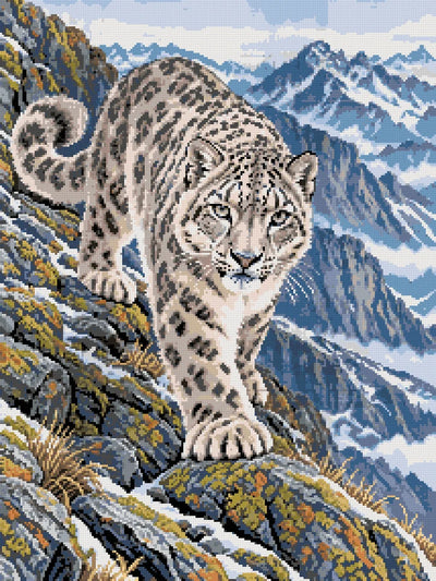 En snöleopard på lavklädda stenar framför blå berg och snöiga dalar