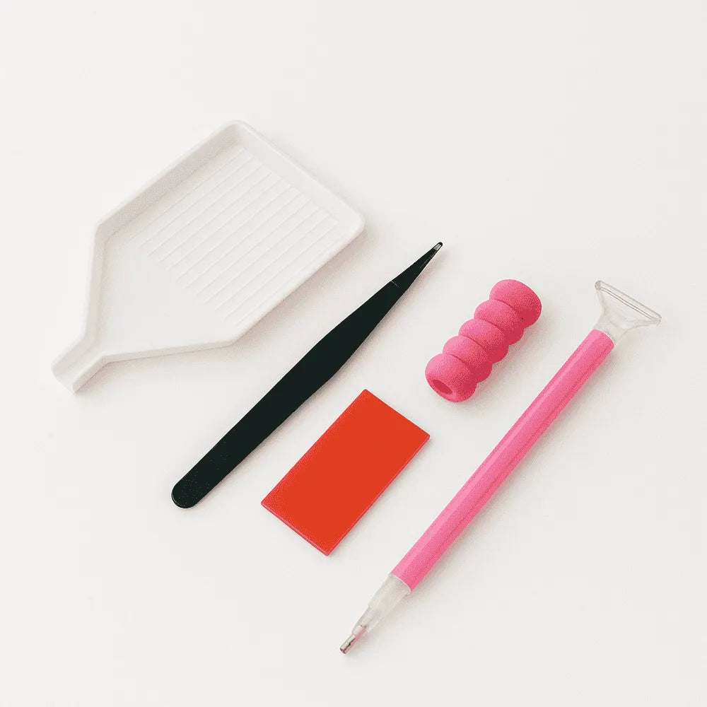 Timanttimaalaustarvikesetti valkoisella taustalla, sisältäen valkoisen helmialustan, mustat pinsetit, punaisen vahalevyn, vaaleanpunaiset sormisuojat ja vaaleanpunaisen kynätyökalun.
