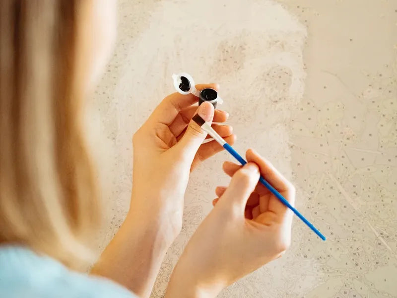 Close-up of paint by numbers being painted with a brush on numbered canvas